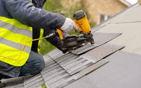 Roofer installing shingles with a nail gun
